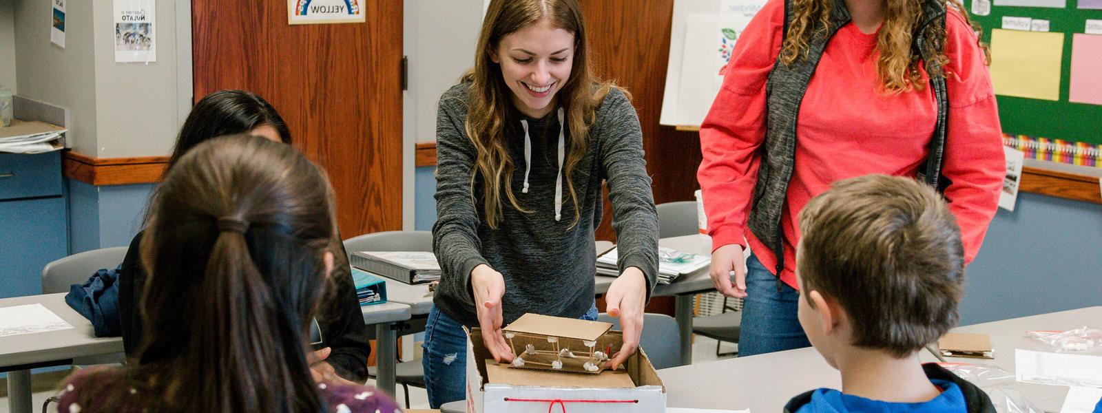 female college student smiles while working on project with kids